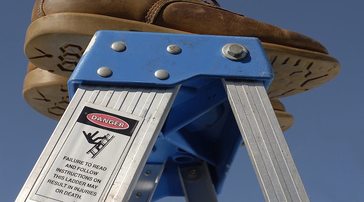 A man stepping on a ladder with cautious label