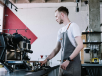 Barista in grey apron using coffee machine