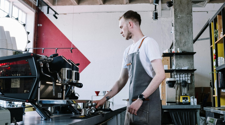 Barista in grey apron using coffee machine