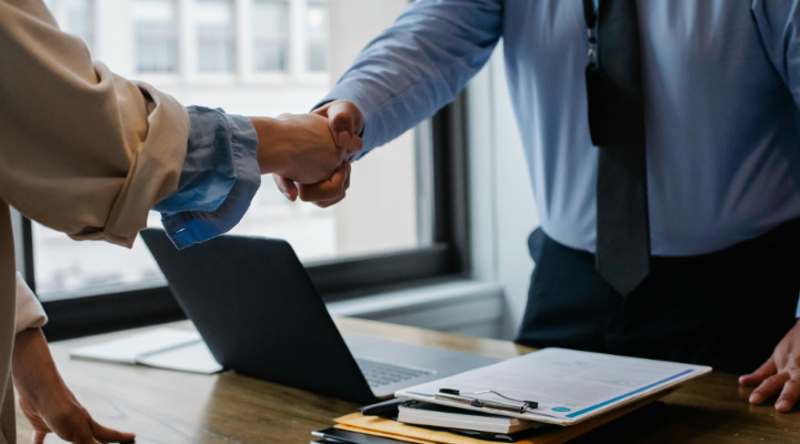 Two businesspeople shaking hands over a desk..