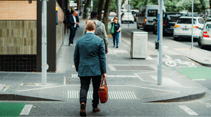 A businessman crosses the road in an Australian CBD