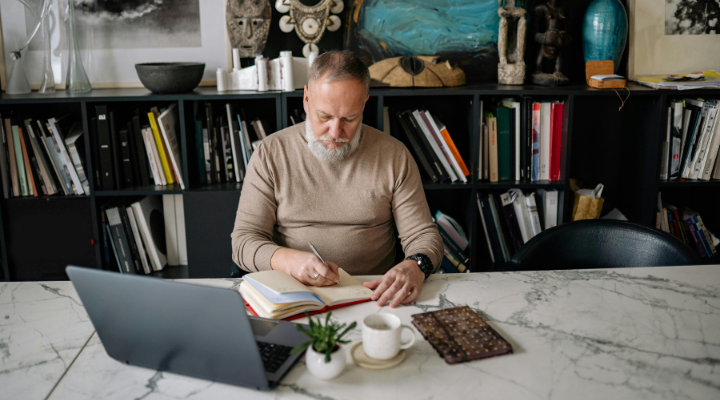Man with grey hair looking down at laptop on desk