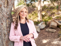 businesswoman-wearing-pink-blazer-leaning-against-tree