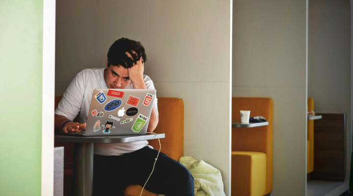 Man sitting on laptop in booth.