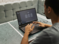 Man using ChatGPT on laptop in grey booth.