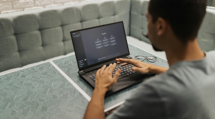Man using ChatGPT on laptop in grey booth.