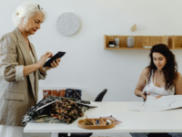 Old and young woman work at table together