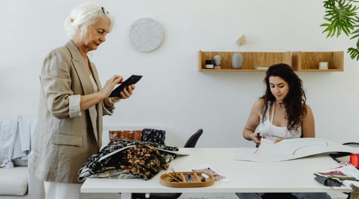 Old and young woman work at table together