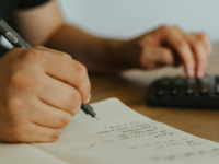 Person doing accounts with notebook and calculator.