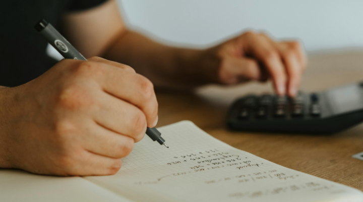 Person doing accounts with notebook and calculator.