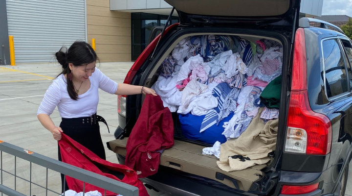 A woman unloading donated clothing from the back of a car.