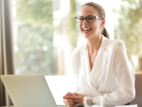 smiling-woman-with-glasses-sitting-at-desk-with-laptop