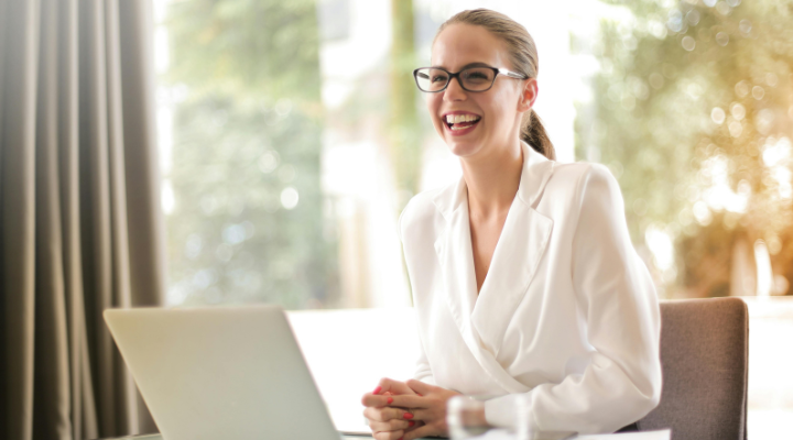 smiling-woman-with-glasses-sitting-at-desk-with-laptop