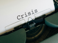 A typewriter printing the word 'crisis'.