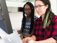 woman-with-red-black-checkered-shirt-typing-into-computer