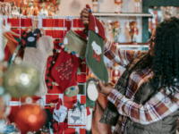 smiling-woman-lifts-christmas-stocking-off-shelf-in-shop
