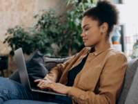 Woman in jacket using laptop on couch