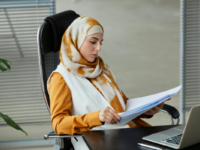 Woman reading files using laptop at desk