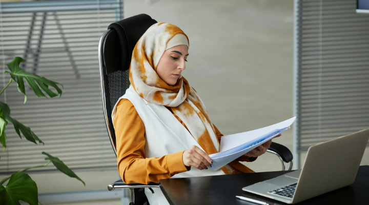 Woman reading files using laptop at desk