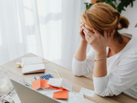 woman-sitting-messy-desk-face-in-hands