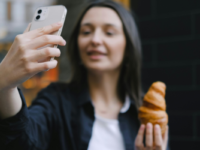 Woman taking a selfie with a croissant.