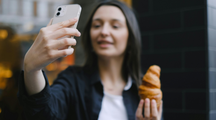 Woman taking a selfie with a croissant.