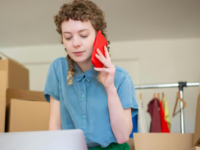 Woman using phone looking down at laptop