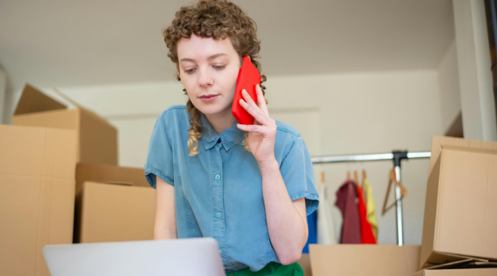 Woman using phone looking down at laptop