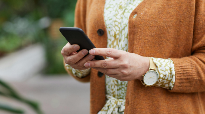 Woman in orange jumper using smartphone.