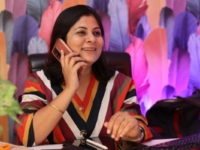 Woman wearing a colourful striped top talks on phone at desk