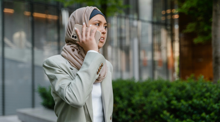Woman wearing hijab and blazer talking on phone.