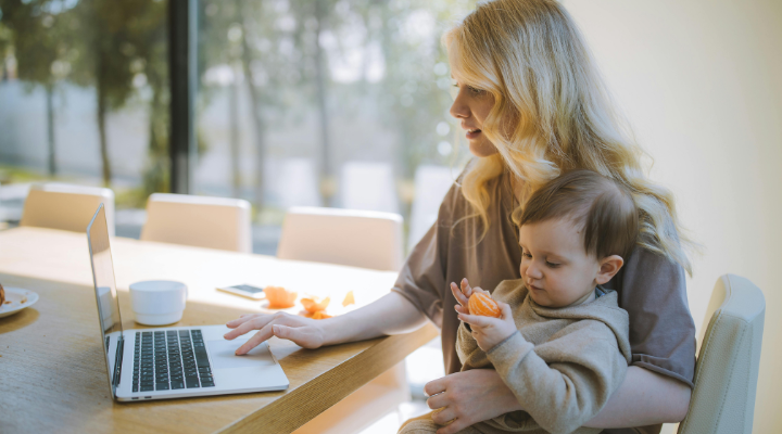 A woman working while holding a baby.